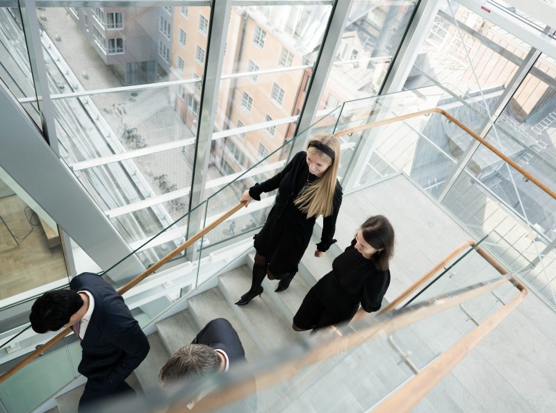 Four people walking down the stairs in office